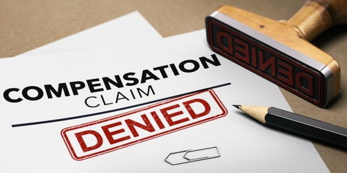Denied compensation claim form with a red 'DENIED' stamp and a stamp tool above it.