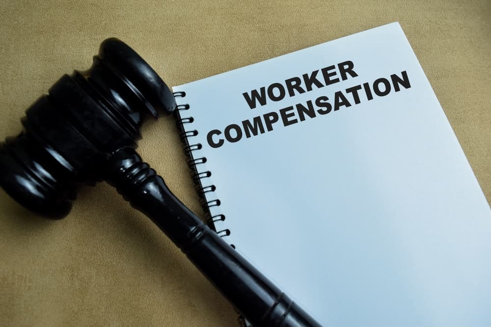 "Concept of Workers' Compensation" written on a book placed on a wooden table.